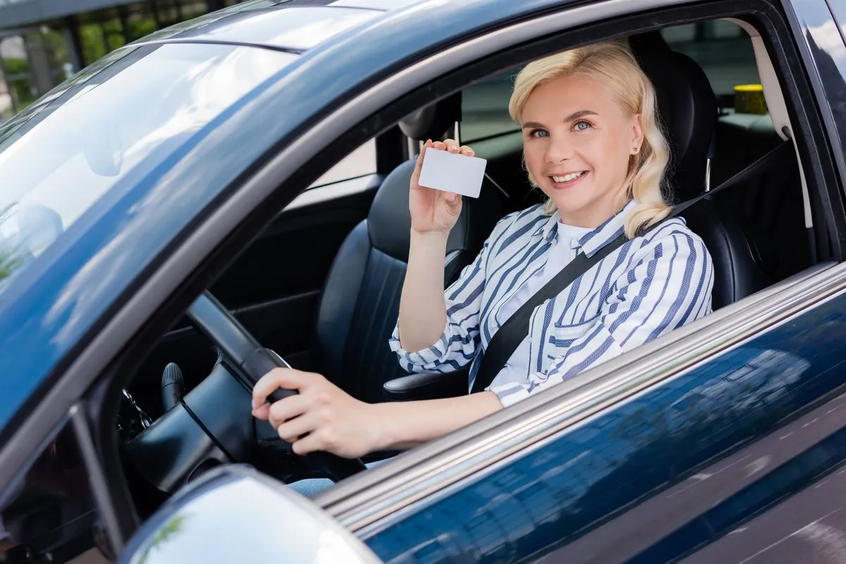 Conductrice souriante présentant son permis au volant