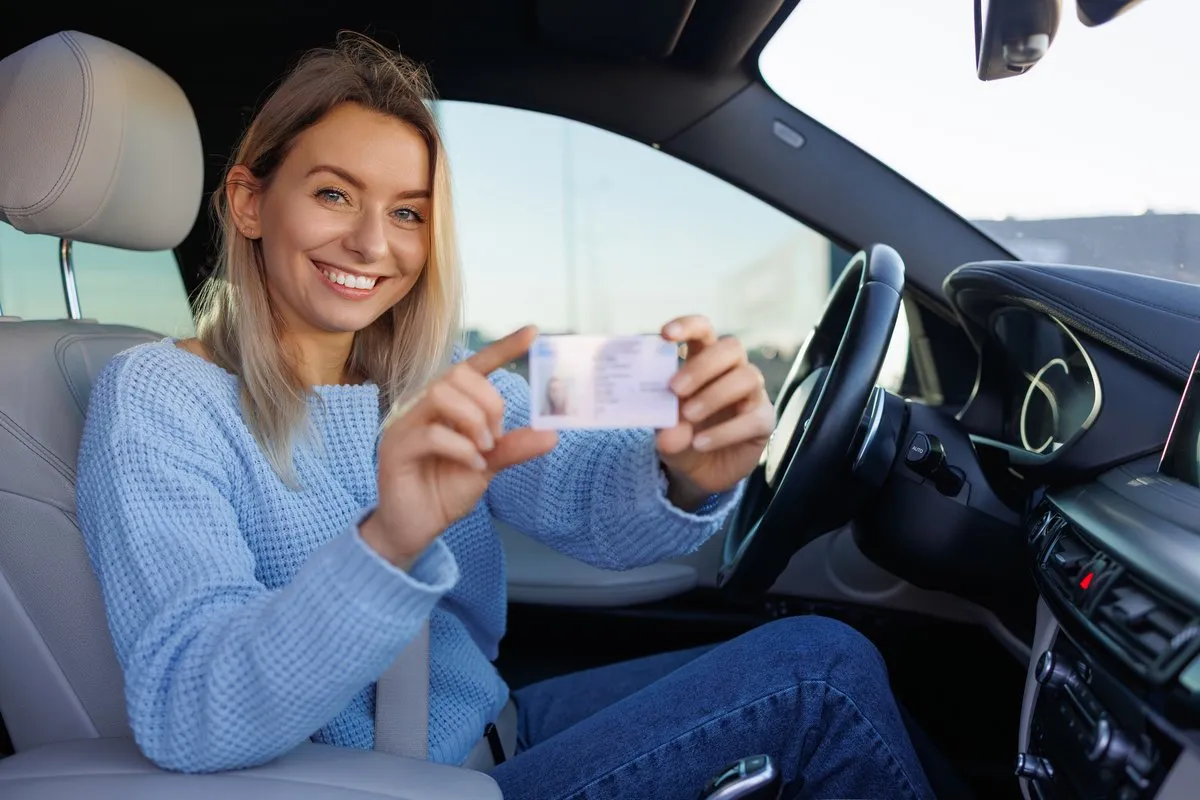 Conductrice souriante montrant son permis de conduire au volant